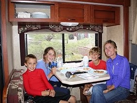 Family of four sitting at their RV table eating a meal