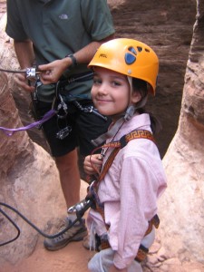 Little girls with a helmet and harness getting ready to climb