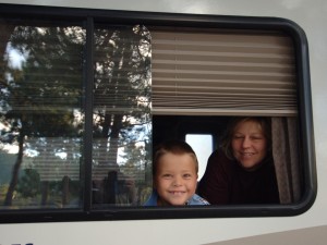 Little boy and mom peeking out of window if their RV