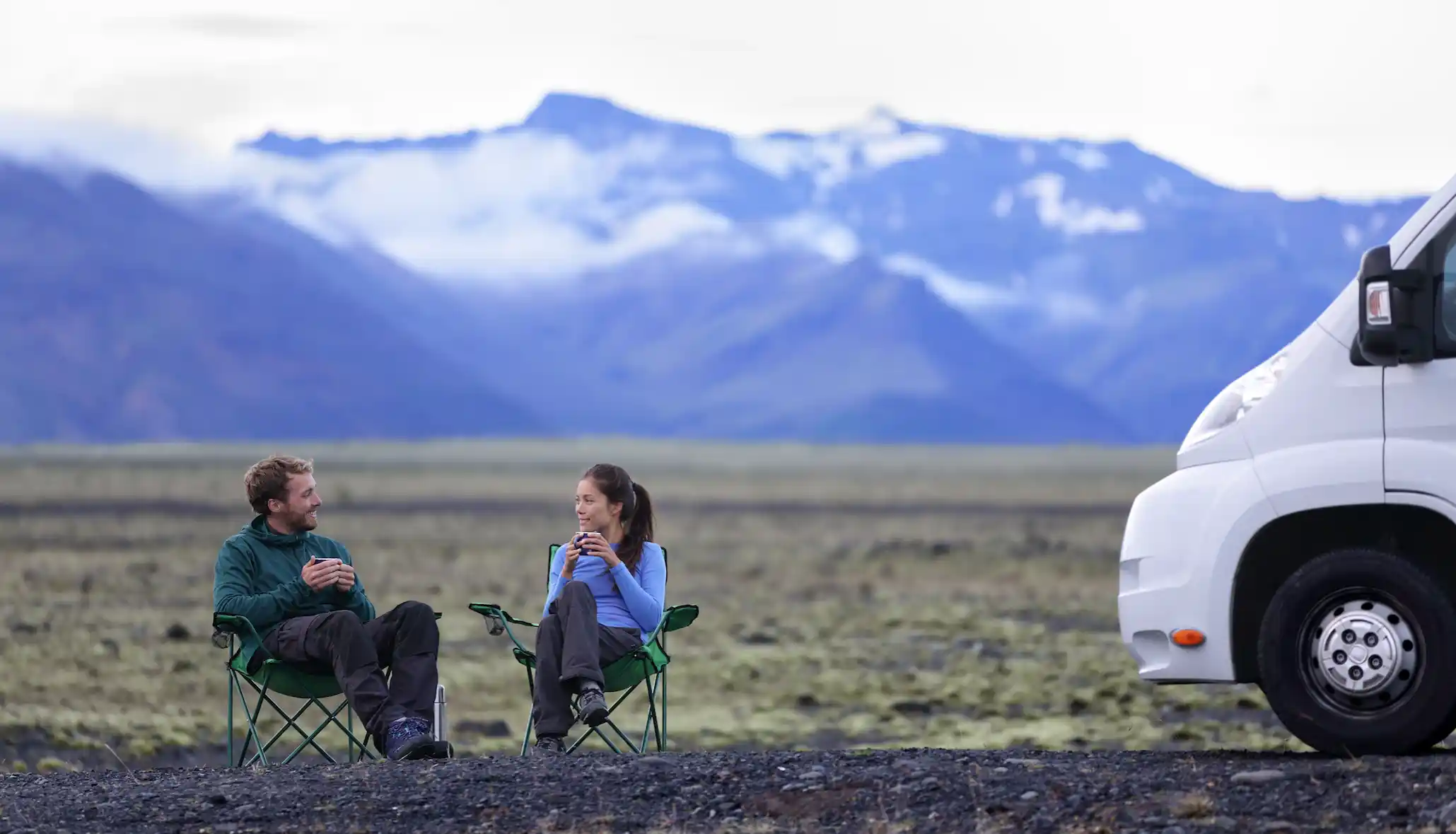 self-drive-rv-vacations man and woman enjoying coffee with mountain range behind them