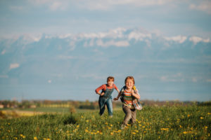 two kids running through field