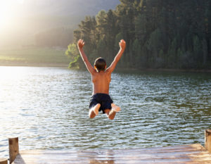 boy jumping into lake