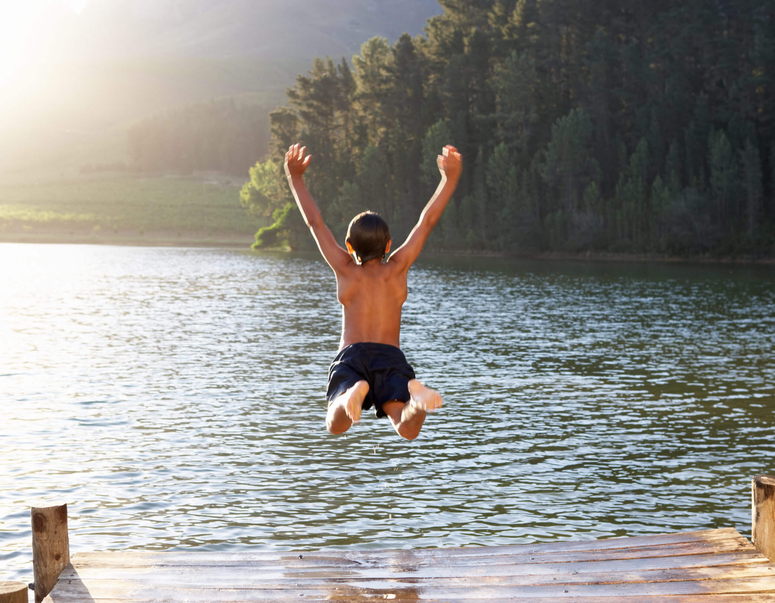 boy jumping into lake