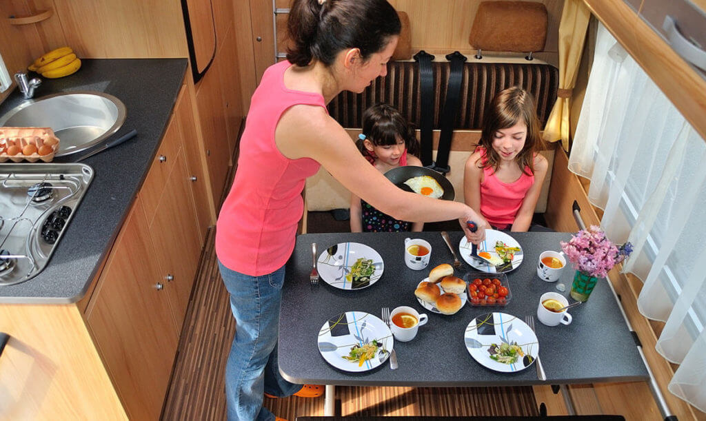 woman and two young girls eating meal inside RV