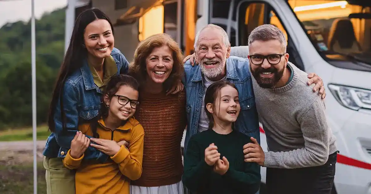 multi generation family standing outside in front of RV looking at camera